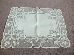 a white doily on the floor with flowers and leaves around it in an ornate frame