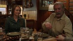 an older man and woman sitting at a table