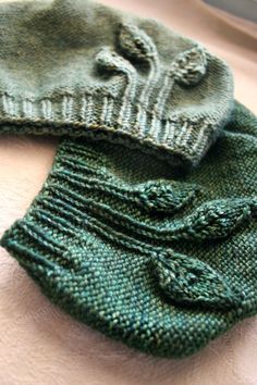 two green knitted mittens laying on top of each other