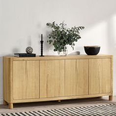 a plant is sitting on top of a wooden cabinet in a room with white walls