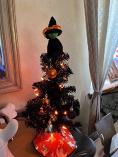 a small christmas tree decorated with lights and decorations in the shape of a witch's hat