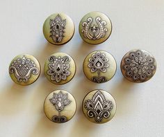 six buttons with designs on them sitting on a table