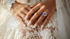 a woman's hands with white nails and a ring on her left hand, wearing a lace dress