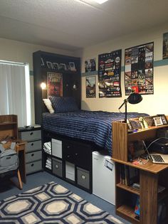 a dorm room with a bed, desk and bookshelf on the wall next to it