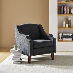 a gray chair sitting on top of a white rug next to a book shelf filled with books