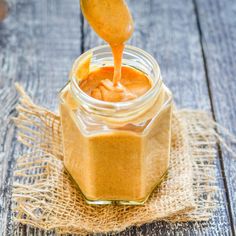 a spoon is pouring peanut butter into a jar