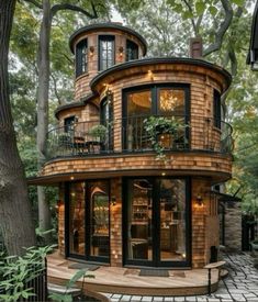 a round house in the middle of a tree filled forest with lots of windows and balconies