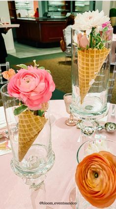 two ice cream cones with flowers in them on a table