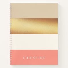 a spiral notebook with gold foil on the front and pink, beige, and white cover