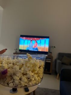 a person holding a bowl of popcorn in front of a television