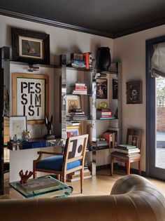 a living room filled with furniture and bookshelves next to a large open window