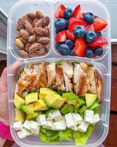 a person holding a plastic container filled with fruit and nuts on top of each other