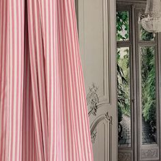 a pink and white striped curtain hanging in front of a door with an ornate mirror behind it