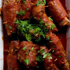 meat covered in sauce and garnished with cilantro on a white plate