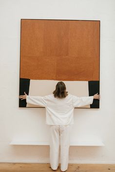 a woman standing in front of a large painting