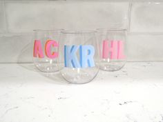 three wine glasses with letters painted on them