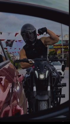 a man riding on the back of a motorcycle next to a pink car in front of him