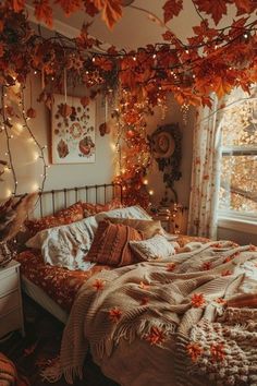 an unmade bed with fall leaves on it and lights strung from the ceiling above