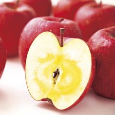 an apple sliced in half with other apples around it on a white surface, showing the core