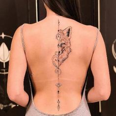 the back of a woman's neck with a fox and arrow tattoo on it