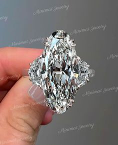 someone is holding a fancy ring with a large diamond in it's middle finger