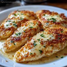 three pieces of chicken covered in cheese on a white plate