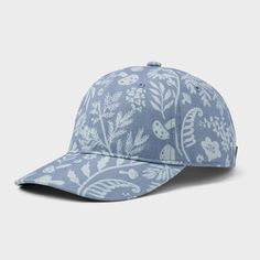 a blue baseball cap with white flowers and leaves on the front, against a gray background