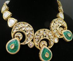 This beautiful choker is a modern twist to traditional jewelry and comes in a gold finish with green stones to match any outfit as desired. The choker is made of high quality stones and is a statement piece that can be dressed accordingly. The set comes with matching earrings for a complete look. Green Gold Plated Kundan Necklace For Festivals, Green Gold-plated Kundan Necklace For Festivals, Elegant Green Kundan Necklace With Jewels, Elegant Green Jeweled Kundan Necklace, Fusion Style Green Bridal Necklace With Hand Set Details, Fusion Style Green Bridal Necklace With Hand Set, Green Fusion Bridal Necklace With Intricate Design, Green Kundan Emerald Necklace With Intricate Design, Green Kundan Necklace With Jewels For Formal Occasions