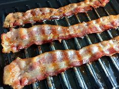 bacon is being cooked on the grill with tongs