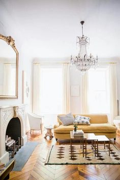 a living room filled with lots of furniture and a chandelier hanging from the ceiling