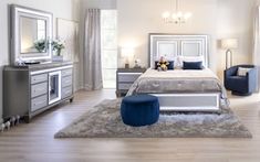 a bedroom with white furniture and blue accents on the bed, dressers, and mirror