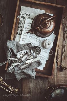 an old tea pot, spoons and other items on a wooden tray with writing