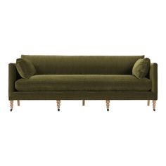 a green velvet couch with wooden legs and two pillows on the back, sitting against a white background