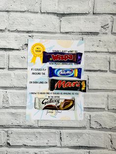 a sign on a brick wall that has various types of candy and chocolate bars attached to it