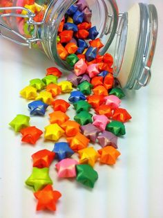 a jar filled with small multicolored stars on top of a table