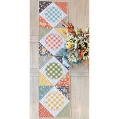 a table runner made with patchwork quilts and flowers on the floor next to it