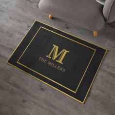 a black and gold door mat with the letter m on it in front of a couch