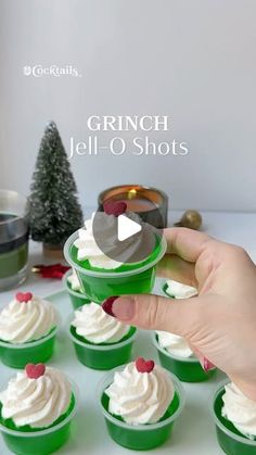 cupcakes with white frosting and red berries being held up by someone's hand