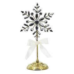 a gold and white snowflake on top of a metal stand with a bow