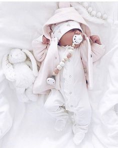 a baby is laying down with a pacifier in it's mouth and wearing a pink hat