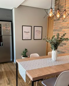 a kitchen with a table, refrigerator and chairs next to each other in front of a brick wall