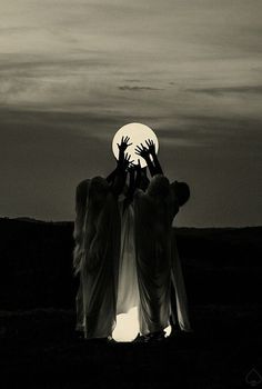 two people are reaching for the moon with their hands in black and white photo by an unknown object