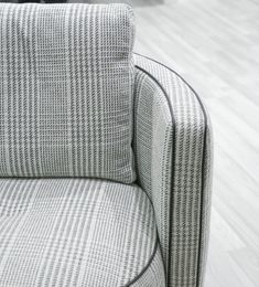 a close up of a chair on a hard wood floor with white and gray fabric