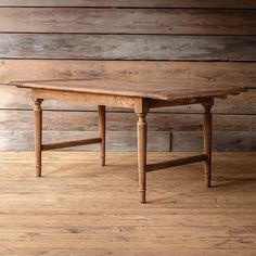 an old wooden table sitting on top of a hard wood floor next to a wall