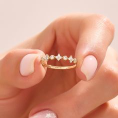 a woman's hand holding a gold ring with three diamonds on it and two fingers