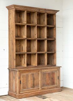 an old wooden bookcase sitting on top of a hard wood floor next to a white wall