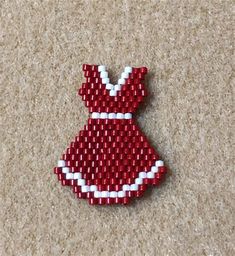 a red and white beaded dress sitting on top of a brown carpeted floor