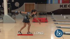 a woman throwing a bowling ball on top of a wooden floor in a bowling alley