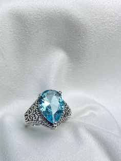 Simulated Sky Blue Aquamarine Gemstone Teardrop RingTear Lace Design#D222 Embrace timeless elegance with this stunning Antique Reproduction ring, inspired by the intricate designs of the Victorian and Art Deco eras. Crafted from premium sterling silver, this exquisite piece showcases a flawless, pear-cut simulated Aquamarine gemstone, measuring 12mm by 10mm. The vibrant blue hue of the aquamarine adds a touch of sophistication and charm. The inside of the band is stamped with 925, confirming its sterling silver composition. Indulge in the beauty and craftsmanship of a bygone era with this gorgeous ring. Elegant Topaz Teardrop Rings, Elegant Teardrop Topaz Gemstone Ring, Elegant Blue Teardrop Topaz Ring, Silver Pear-shaped Blue Topaz Jewelry, Silver Pear-shaped Blue Topaz Rings, Formal Teardrop Blue Topaz Ring, Elegant Teardrop Topaz Ring, Teardrop Topaz Promise Ring, Formal Teardrop Topaz Rings