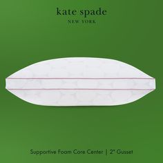 a white pillow sitting on top of a green background with the words kate spade new york